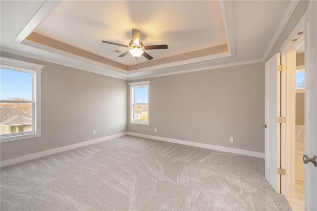 unfurnished room featuring a tray ceiling, ornamental molding, light colored carpet, and ceiling fan