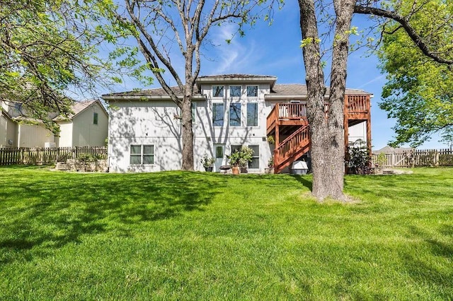 back of property featuring a yard, fence, a wooden deck, and stairs