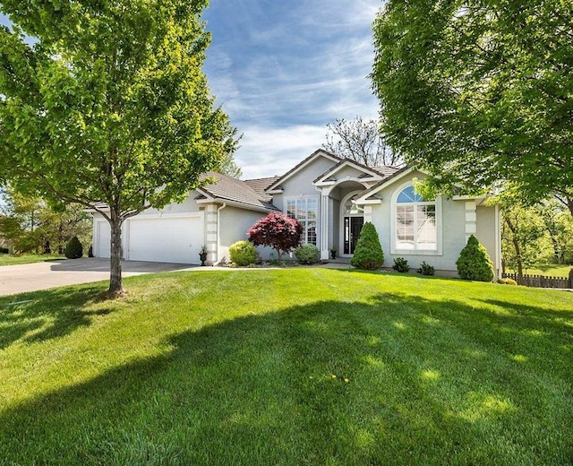 ranch-style home featuring a garage, a front yard, driveway, and stucco siding