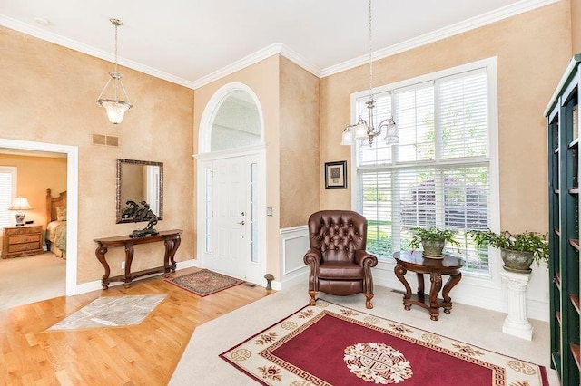 entryway with ornamental molding, wood finished floors, visible vents, and an inviting chandelier