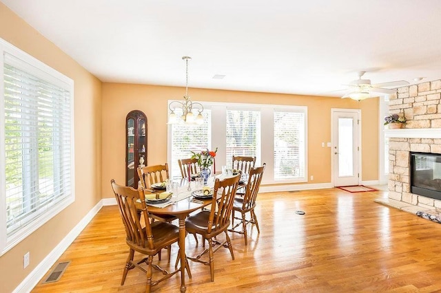 dining room featuring light wood-type flooring, a fireplace, visible vents, and a healthy amount of sunlight