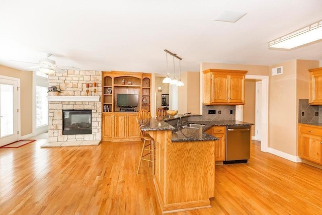 kitchen featuring dishwasher, a kitchen island, open floor plan, decorative light fixtures, and a sink