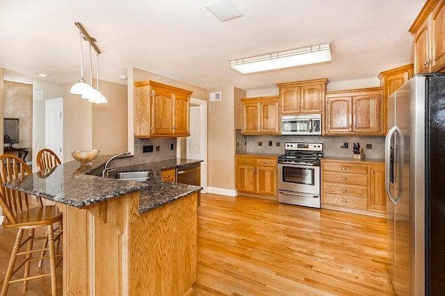 kitchen with brown cabinets, a kitchen bar, stainless steel appliances, and a sink