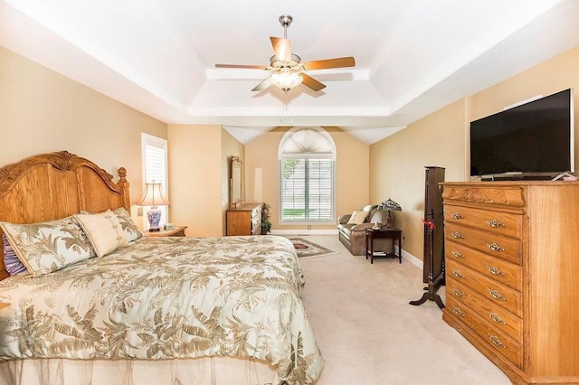 bedroom featuring a ceiling fan, a tray ceiling, light carpet, and baseboards