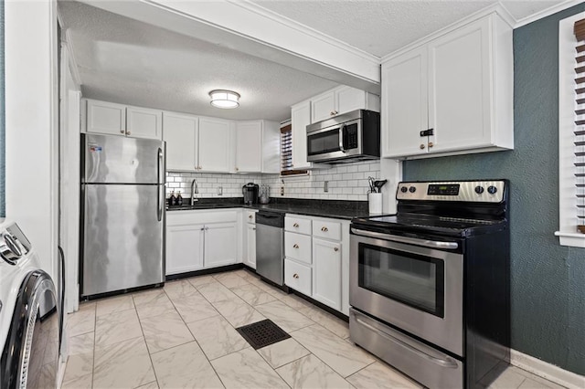 kitchen with decorative backsplash, white cabinetry, stainless steel appliances, and washer / dryer