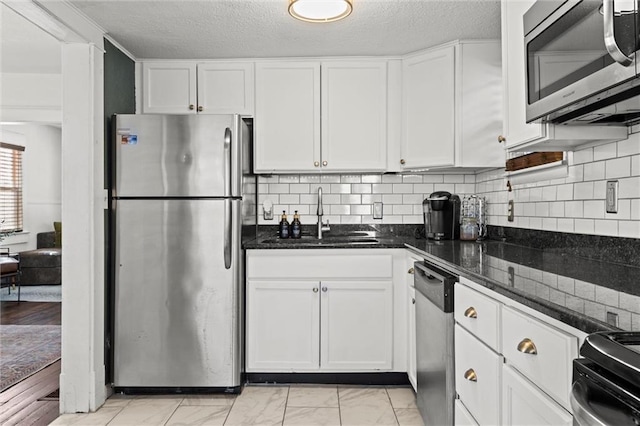 kitchen with dark stone countertops, sink, appliances with stainless steel finishes, white cabinets, and decorative backsplash