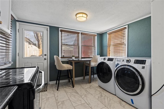 clothes washing area featuring washing machine and dryer, ornamental molding, and a textured ceiling