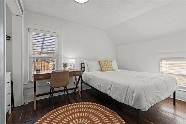 bedroom with vaulted ceiling, dark hardwood / wood-style floors, and a textured ceiling