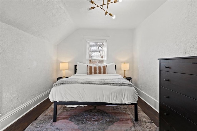 bedroom featuring hardwood / wood-style flooring, vaulted ceiling, and a chandelier