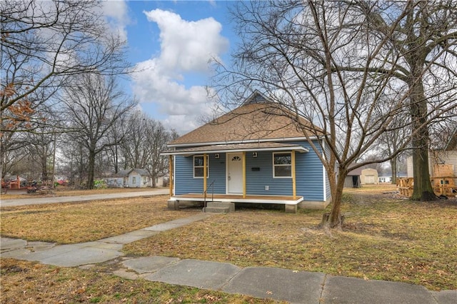 bungalow featuring covered porch, roof with shingles, and a front yard