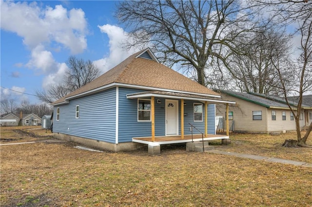 bungalow-style house featuring a front yard, covered porch, roof with shingles, and crawl space