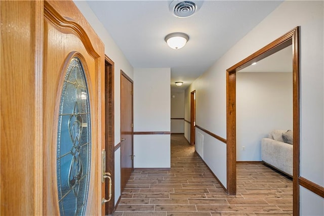 hallway featuring wood finish floors and visible vents