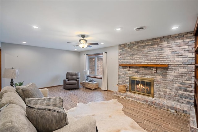 living room with light wood-style flooring, a fireplace, visible vents, and recessed lighting