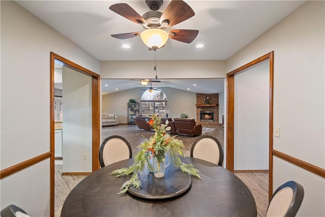 dining room with light wood-type flooring, a fireplace, and recessed lighting