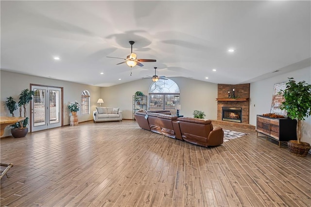 living area with french doors, a fireplace, lofted ceiling, recessed lighting, and wood finished floors