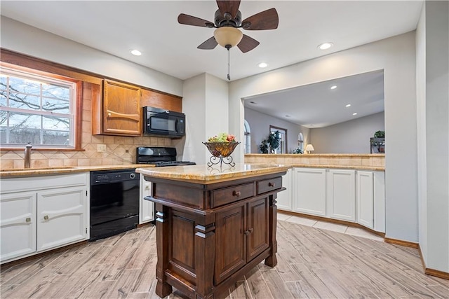 kitchen with light countertops, backsplash, white cabinets, a sink, and black appliances