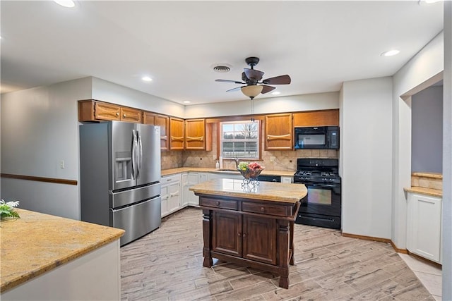 kitchen with a sink, visible vents, light countertops, black appliances, and brown cabinetry