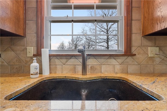 details featuring light stone counters, brown cabinets, a sink, and decorative backsplash