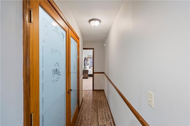 corridor with baseboards and wood finished floors