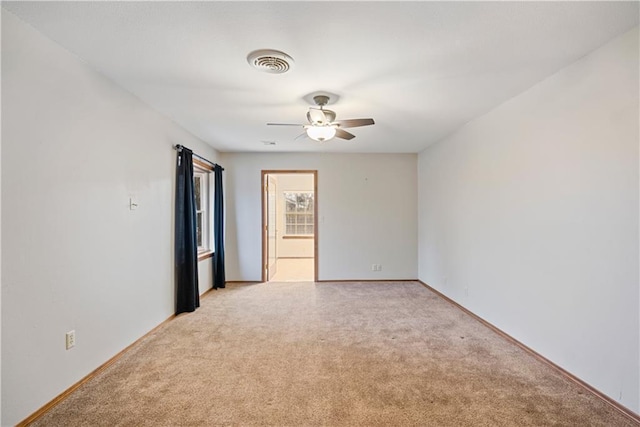 unfurnished room featuring baseboards, a ceiling fan, visible vents, and light colored carpet