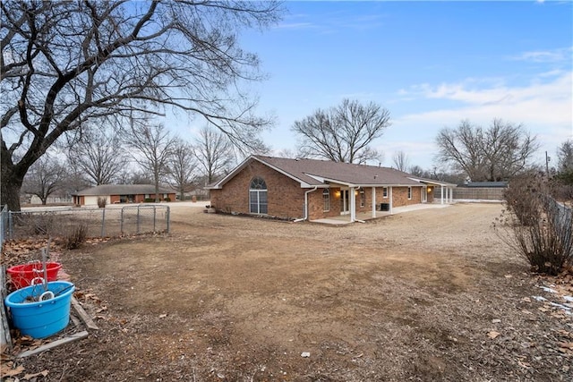 rear view of property featuring brick siding and fence