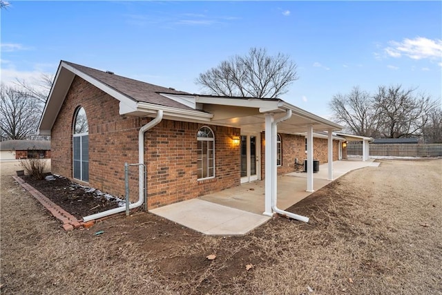 view of home's exterior with a patio area, brick siding, and fence