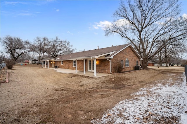 back of house featuring cooling unit, brick siding, and a patio