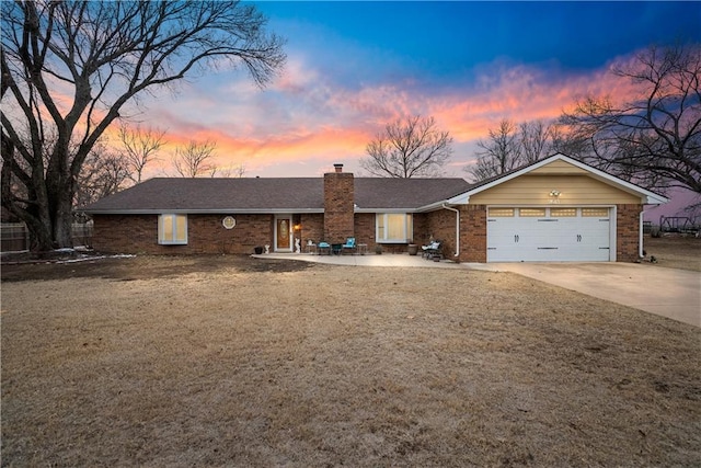 ranch-style house with an attached garage, brick siding, driveway, a lawn, and a chimney