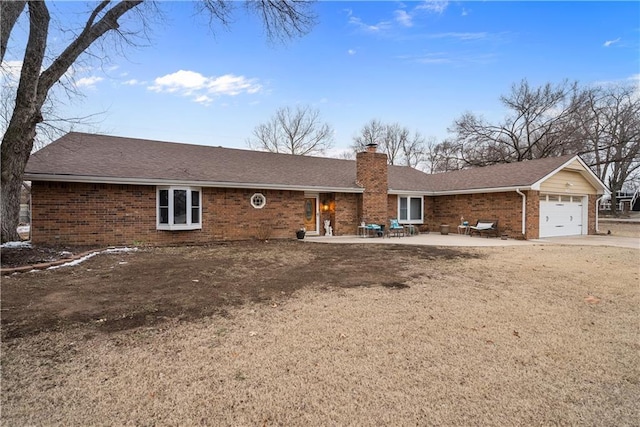 view of front facade with brick siding, a chimney, a shingled roof, an attached garage, and a patio area