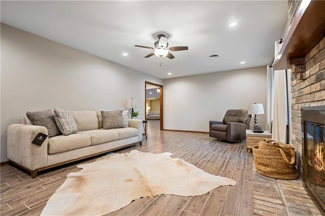 living area featuring ceiling fan, recessed lighting, wood finished floors, a brick fireplace, and baseboards