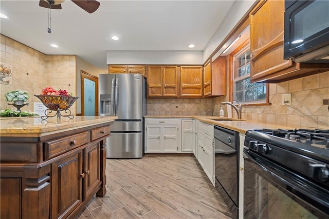 kitchen featuring light stone counters, backsplash, black appliances, ceiling fan, and a sink