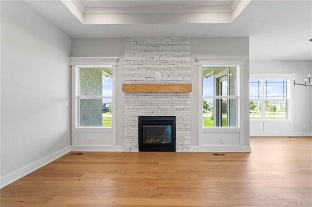 17151 W 168th Pl, Olathe, KS 66062 - unfurnished living room featuring hardwood / wood-style flooring, a tray ceiling, a fireplace, and healthy amount of natural light