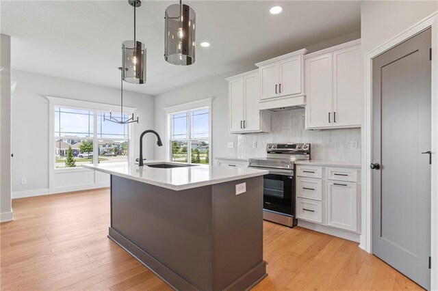 17151 W 168th Pl, Olathe, KS 66062 - kitchen featuring stainless steel electric range, under cabinet range hood, light countertops, an island with sink, and backsplash