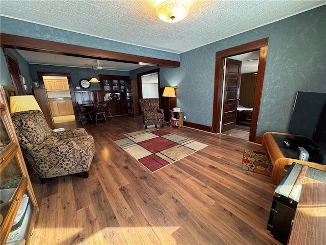 living area with dark wood-type flooring, a textured wall, and baseboards