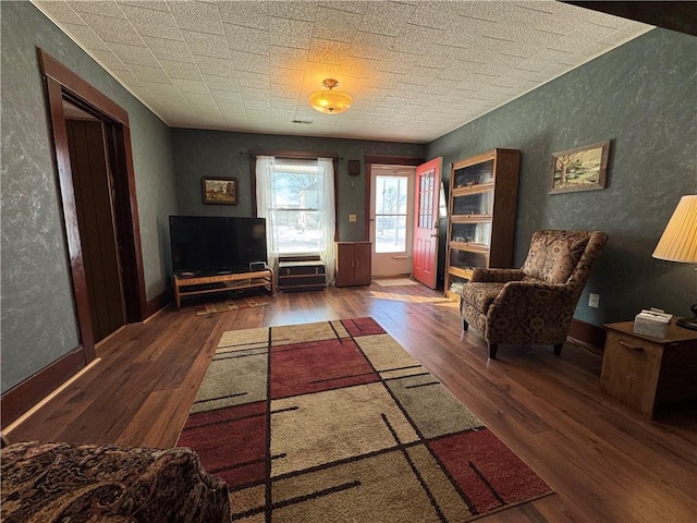 sitting room featuring baseboards, dark wood-type flooring, and a textured wall