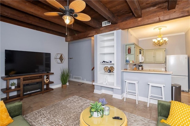 living room featuring built in shelves, beam ceiling, light tile patterned floors, crown molding, and ceiling fan with notable chandelier