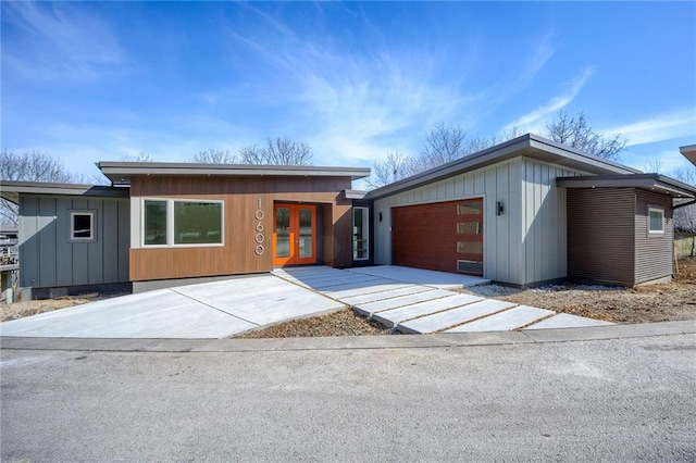 contemporary house with french doors, board and batten siding, concrete driveway, and an attached garage