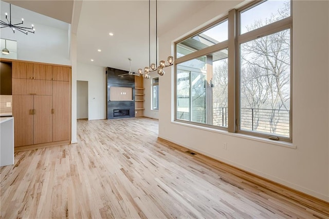 unfurnished living room featuring light wood-type flooring, visible vents, a notable chandelier, recessed lighting, and baseboards