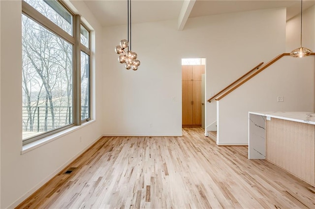 interior space featuring baseboards, visible vents, light wood-style flooring, beamed ceiling, and a chandelier