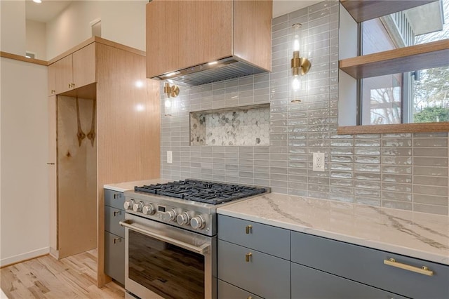 kitchen featuring backsplash, light wood-type flooring, light stone counters, gray cabinets, and stainless steel range