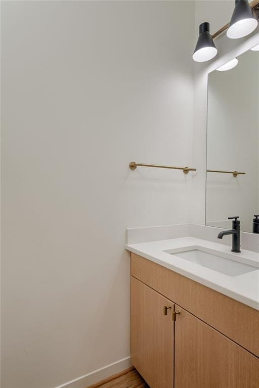 bathroom with vanity, wood finished floors, and baseboards