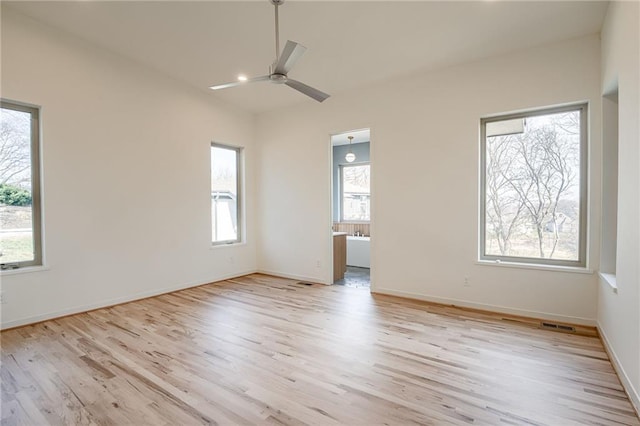 spare room featuring light wood-type flooring, baseboards, a healthy amount of sunlight, and a ceiling fan