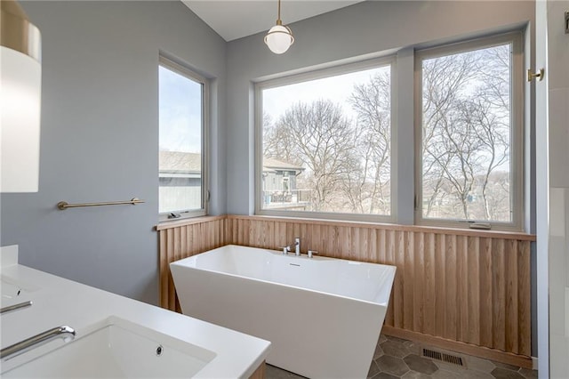 bathroom featuring visible vents, a wainscoted wall, a sink, wooden walls, and a freestanding bath