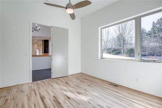 unfurnished room with visible vents, ceiling fan, and wood finished floors