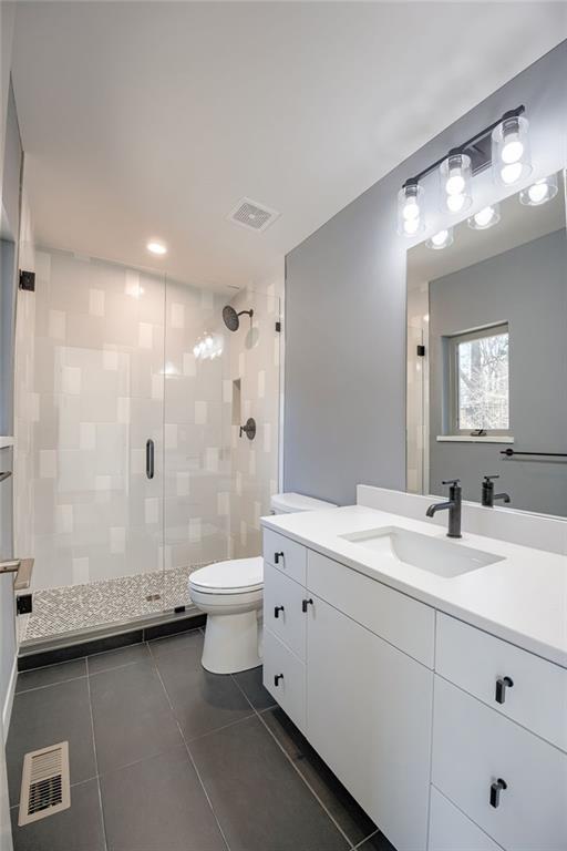 full bathroom with tile patterned flooring, visible vents, a stall shower, and toilet