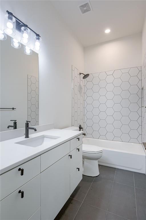 bathroom featuring tile patterned floors, visible vents, toilet, tub / shower combination, and vanity