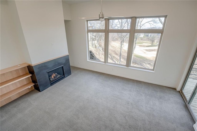 unfurnished living room featuring plenty of natural light, carpet, and a glass covered fireplace