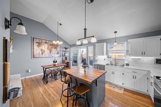 kitchen with a kitchen island, a sink, white cabinetry, dishwasher, and pendant lighting