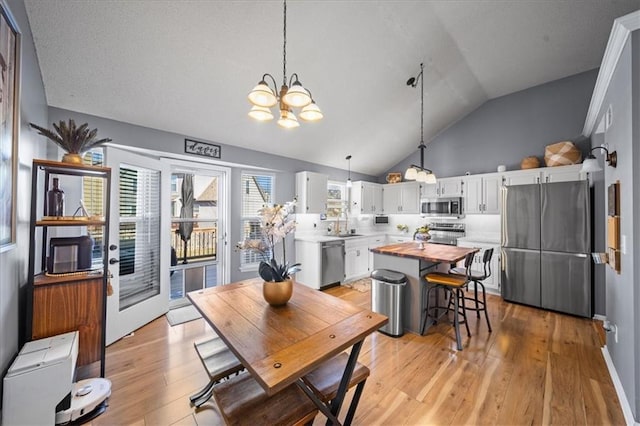 dining area featuring vaulted ceiling, a notable chandelier, and light wood-style floors