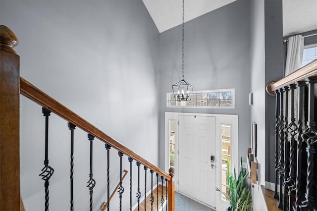 foyer entrance featuring stairs, high vaulted ceiling, and a chandelier